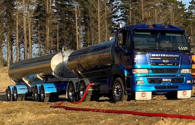 Tapped Out water tanker parked in pine forestry clearing pumping water