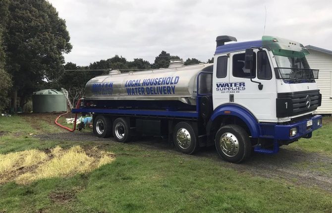 Tapped Out water truck connected to a green tank at a residential property