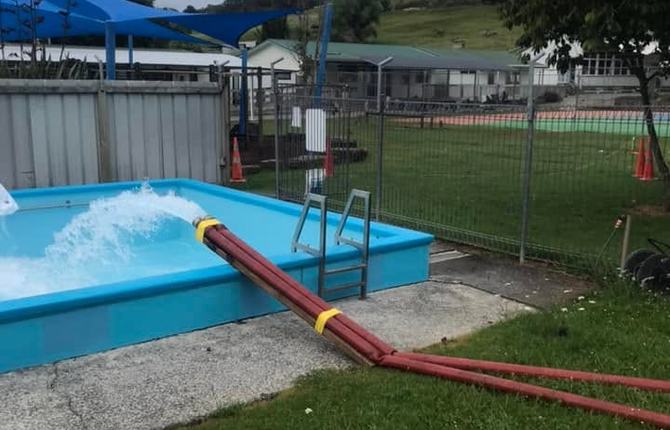 Water pumping into a swimming pool through Tapped Out delivery hoses laid across the grass