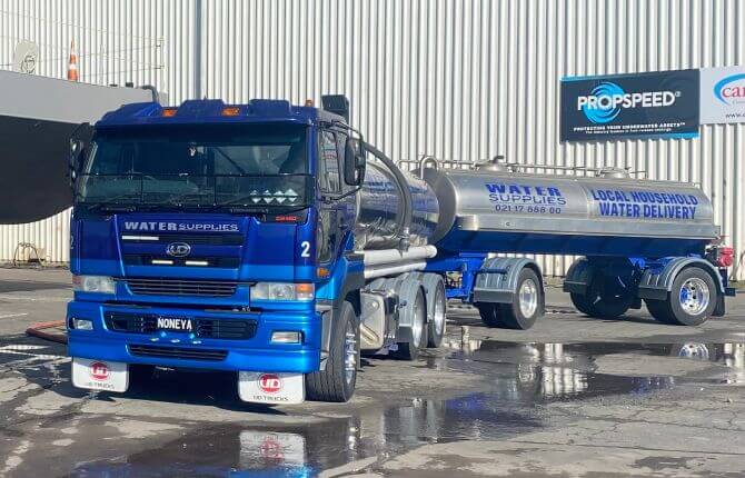 Tapped out water truck and tanker parked in front of commercial building
